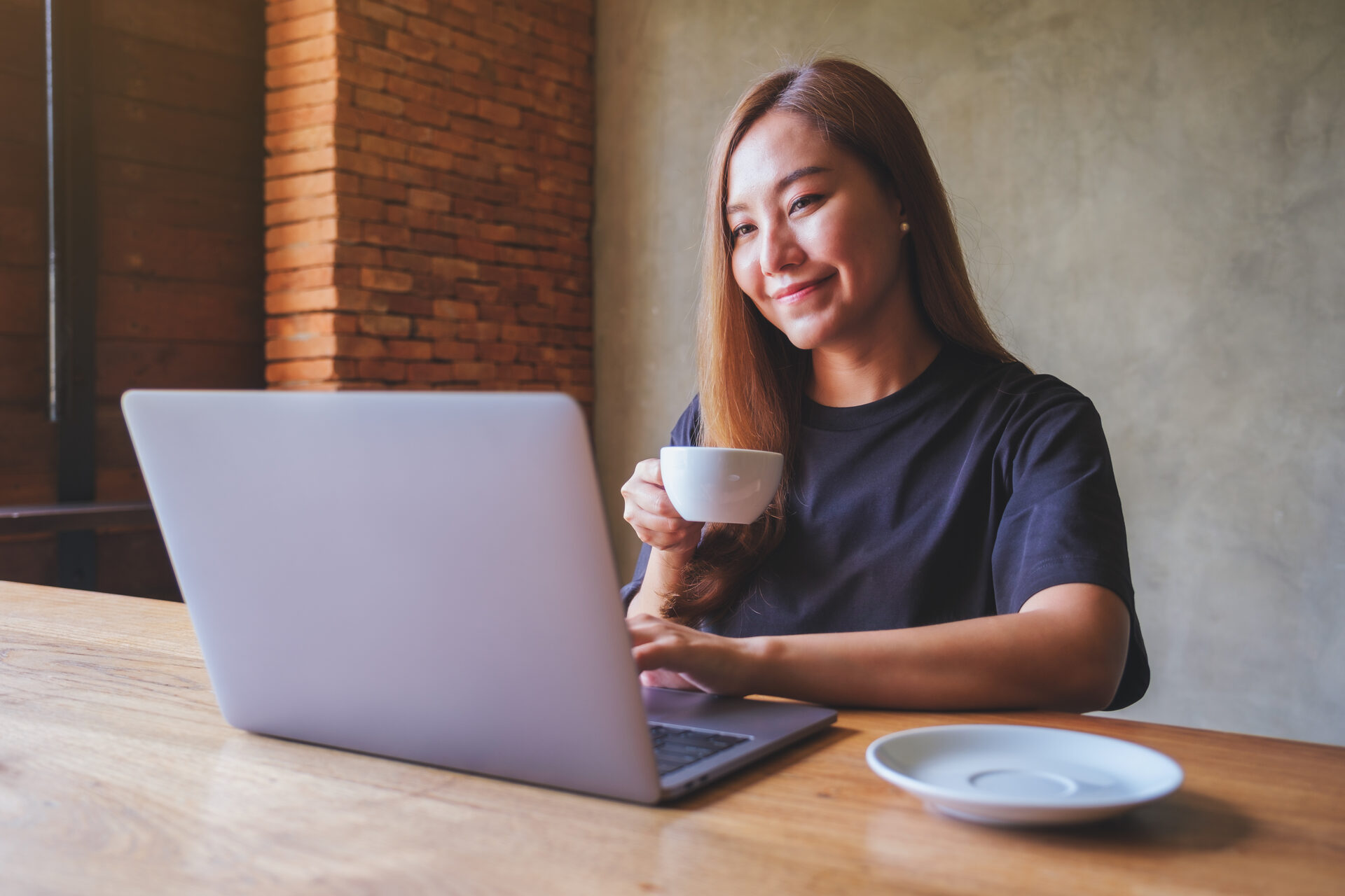 A user smiling at a laptop with a coffee